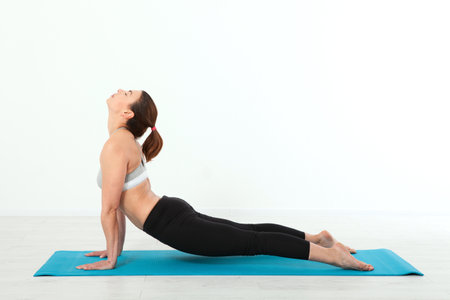 Close up of young woman practicing yoga, sitting in exercise, yoga pose, working out, wearing sportswear, black pants, grey bra, indoor, fitness class interior background. Concept people are workout in yoga, training in sports clothes isolatedの写真素材