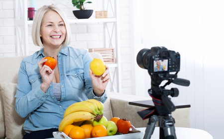 Happy woman expert nutritionist shows fruits to the camera at home.の写真素材