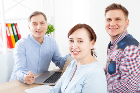A group of businessmen in the office look at the camera and smile.の写真素材