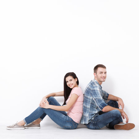 Happy young couple sitting on floor looking up while dreaming their new home and furnishing. Mock up for design.の写真素材