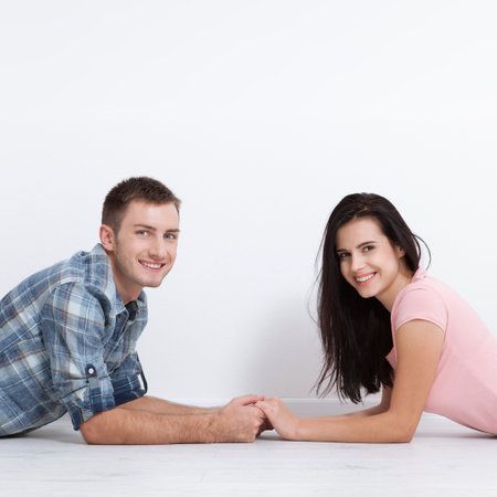 Happy young couple, lying on the floor, look at each other and dream of furniture for new apartment. Mock up for design.の写真素材