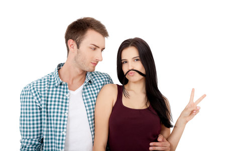 Playful couple fooling on valentine day. Beautiful young loving couple bonding to each other and smiling while making fake mustaches from her hairの写真素材