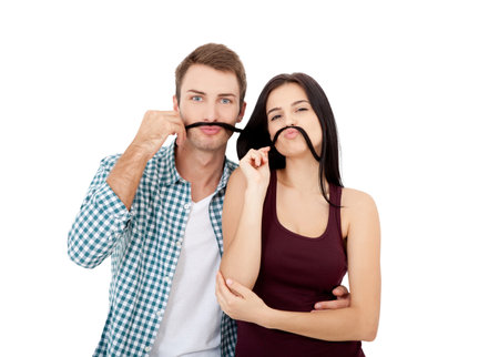Playful couple fooling on valentine day. Beautiful young loving couple bonding to each other and smiling while making fake mustaches from her hairの写真素材
