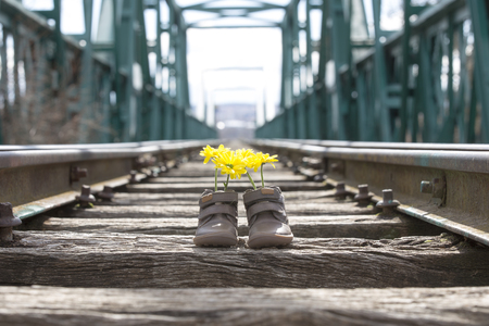 Baby shoes with yellow flowers on an iron bridgeの写真素材