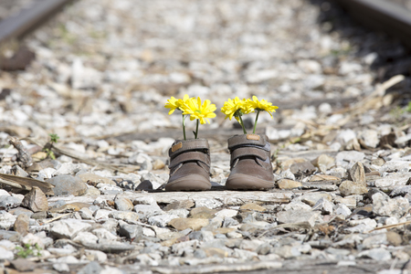 Baby shoes with yellow flowers on an iron bridgeの写真素材