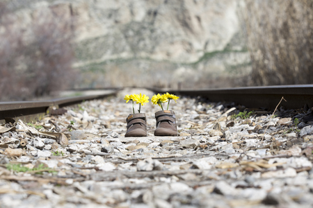 Baby shoes with yellow flowers on an iron bridgeの写真素材