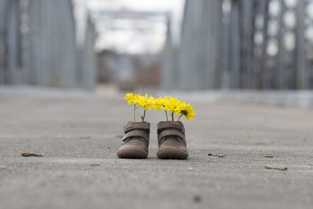Baby shoes with yellow flowers on an iron bridgeの写真素材