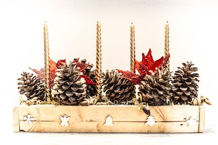 Christmas center with pine cones, acorns, candles and red flowersの写真素材