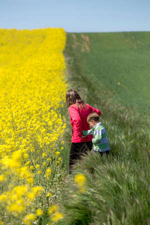 Mother and son walking through the rapeseed field.の写真素材