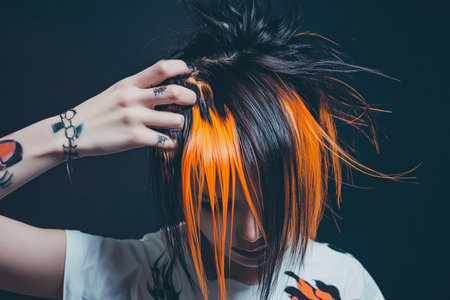 Portrait of a punk girl with bright orange hair on a black backgroundの素材