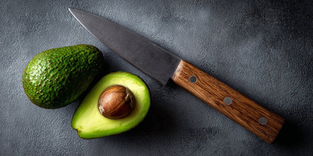 Avocado and knife on a dark background. Top view, copy spaceの素材