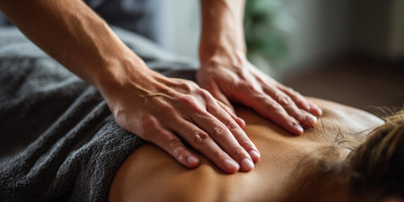 Close-up of masseur hands doing back massage to woman in spa salonの素材