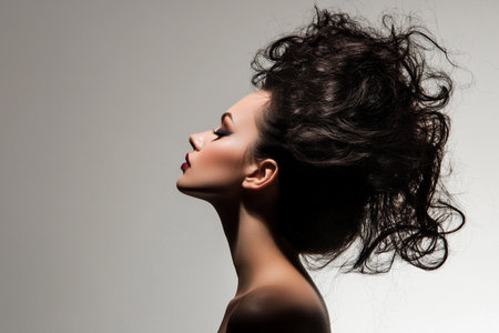 Beautiful young woman with long black hair on a gray background.の素材