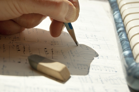 hand of composer writing and editing music closeup shotの写真素材