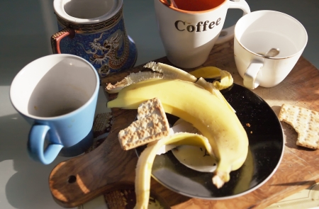 dirty dishware and cups with banana skin and bitten bisquitsの写真素材