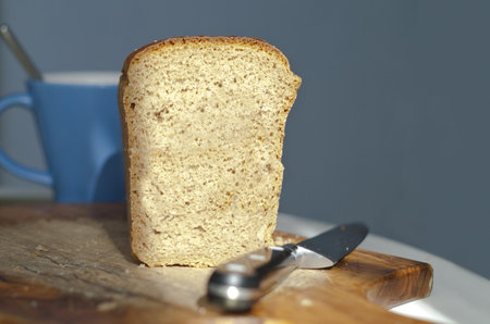 close up shot of a sliced bread with knife and cup and blue background