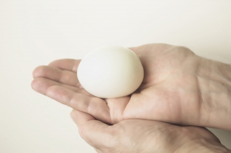 hand holding a peeled egg, close up studio shot on whiteの写真素材