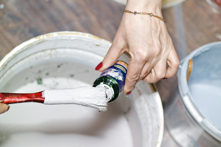 woman`s hand mixing colors in some tin of paintsの写真素材