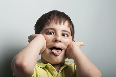 portrait of a naughty boy, teasing you with a chewing gum in a mouth, concept of misbehaveの写真素材