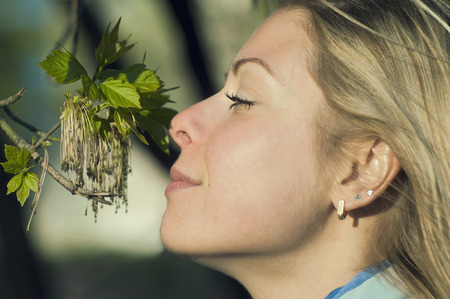 closeup of a happy young woman smelling blossoming rowan tree, concept of tenderness, outdoor side shotの写真素材