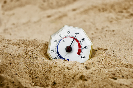 Retro thermometer with analogue scale in a desert, close up shot with blurred foreground and background, concept of climate changeの写真素材