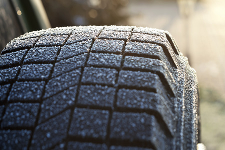 Close up of the ice and snowflakes on a spare tire, winter scene, concept of driving in bad weatherの写真素材