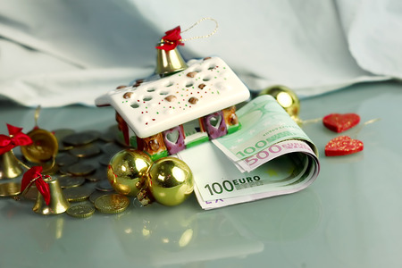 Christmas House with euro banknotes and coins around, concept of holidays expenses and giftsの写真素材