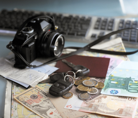 Cash, photo camera, car keys over a travel map, tourism concept, indoor shot with selective focusの写真素材