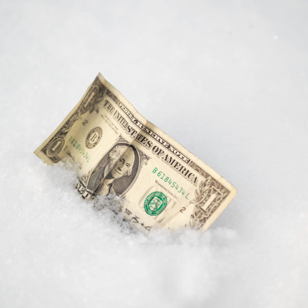 Close up of a crumpled dollar bill in a snow, lost and found  conceptの写真素材