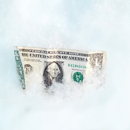 Close up of a crumpled dollar bill in a snow, business conceptの写真素材