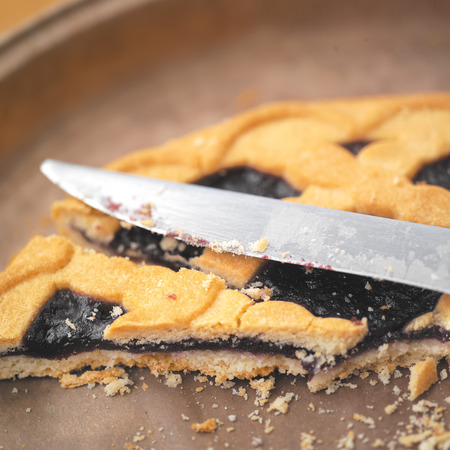 Close up of a blackcurrant pie with a kitchen knife over it, indoor shot with a shallow DOFの写真素材