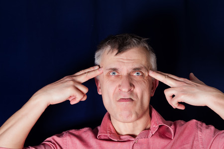 Studio portrait of a man pointing hand gun at his own head, concept of desperationの写真素材
