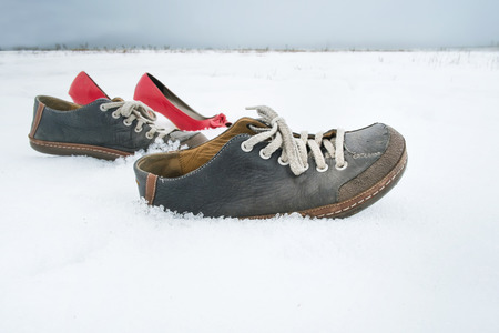Men and ladies shoes walking on snow without people, concept of beyond beliefの写真素材