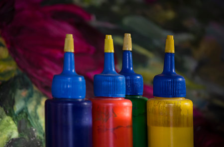 Closeup of mottled plastic bottles for paint, canvas with painting in the blurred background. Indoor shot with a shallow depth of fieldの写真素材