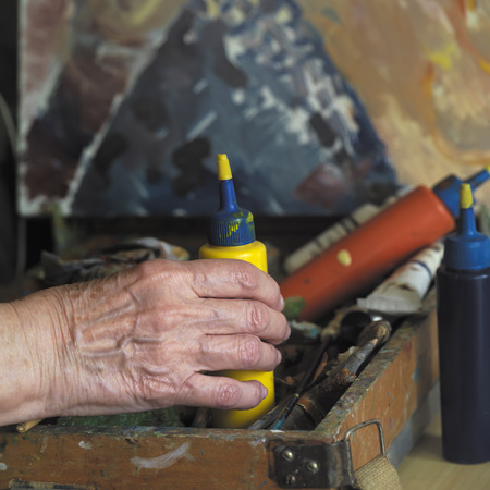 Hand of female artist taking a color bottle from a artist box, studio in the blurred backgroundの写真素材