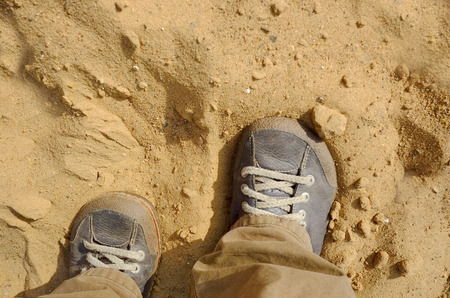 Overhead shot of the human legs wearing shoes stuck in the sand concept of climate changeの写真素材