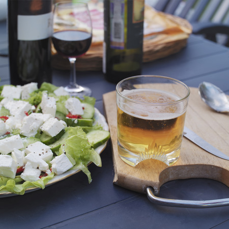 Beer glass, salad and wine laid on a table, outdoor square shot with selective focusの写真素材