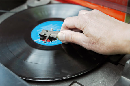 Closeup of a DJ hand on the turntable deck, outdoor shot with selective focus