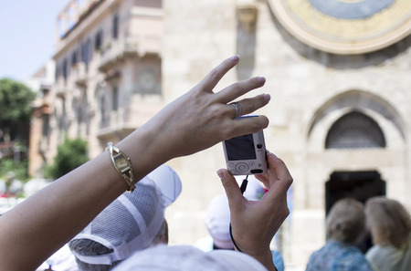 Hands of woman taking pictures on mobile phone or small photo camera city scape in the blurred backgroundの写真素材