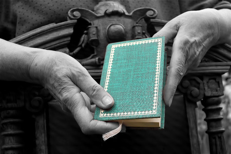 Female hands leaning on a retro chair and holding a green book black and white shot with green accent on the bookの写真素材