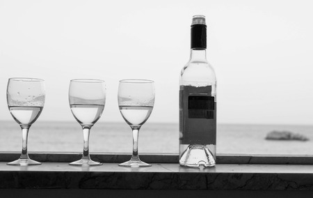 Bottle of abstract alcohol drink and glasses on a window sea in the blurred background.の写真素材