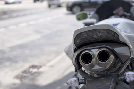 Closeup of the exhaust pipes of motorcycle, parked on a street, city traffic in the blurred backgroundの写真素材