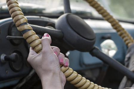 Closeup of female hand with red manicure on a retro wheel, selective focus horizontal shotの写真素材