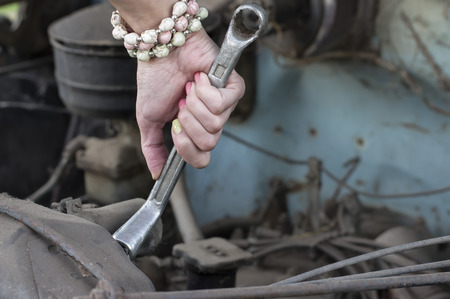 Closeup of a female hand holding wrench next to car radiator, concept of cars repairの写真素材