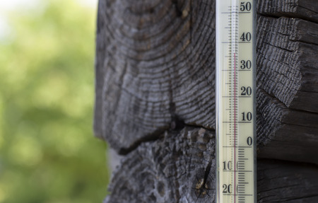Old mercury thermometer indicating  a high temperature, concept of climate change, outdoor shot with blurred backgroundの写真素材