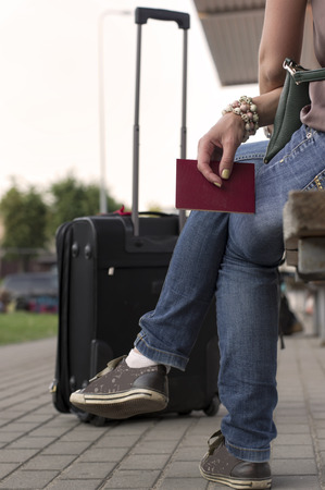 Woman waiting for transport with passport in hands, outdoor vertical shotの写真素材