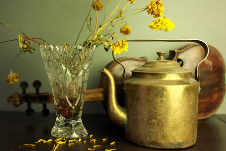 Faded flowers in vase, retro kettle and violin in the background, indoor horizontal shotの写真素材