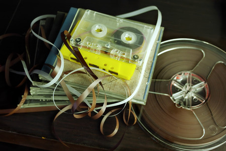 Closeup of reel to reel tape, compact cassettes and CDs on the tableの写真素材