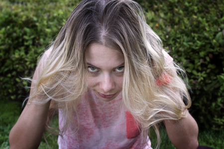Young female with long white hair and sullen gaze, green park in the blurred backgroundの写真素材