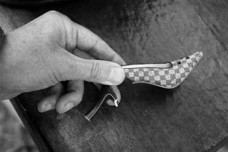 Broken ladies toy high heel in male hand, closeup shot in black and whiteの写真素材